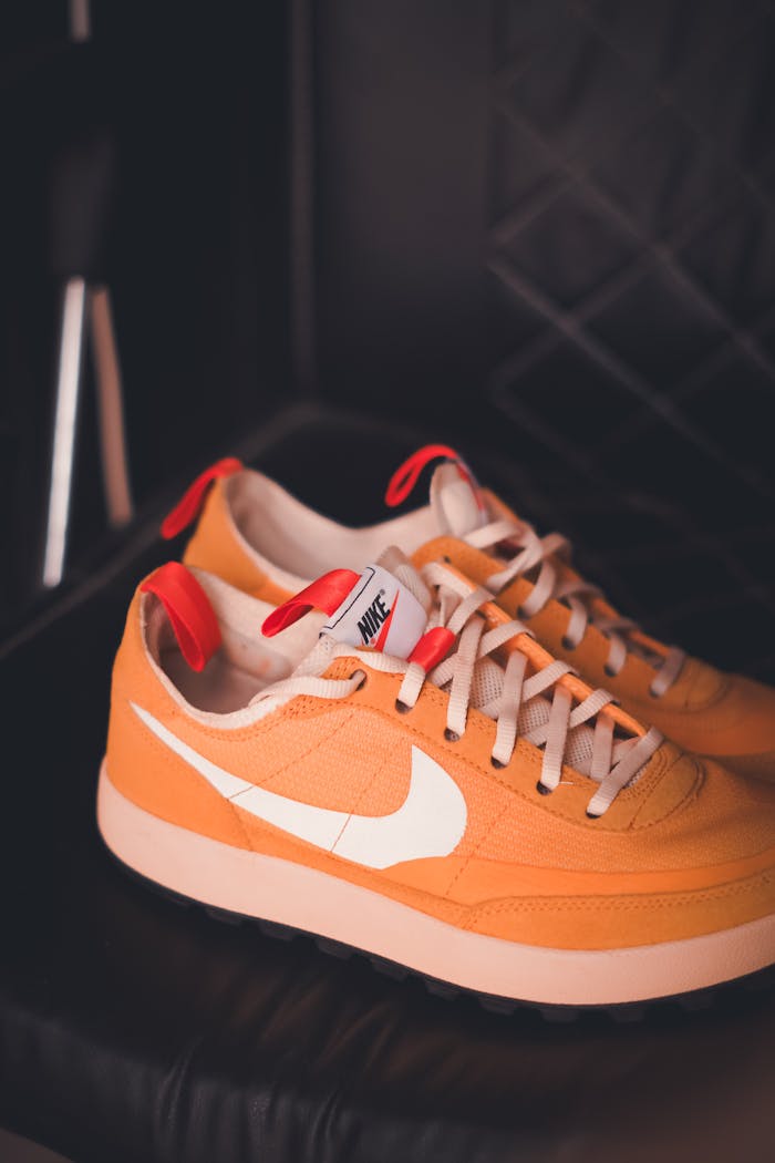 Crafting Captivating Headlines: Your awesome post title goes here Stylish orange sneakers with white swoosh against a dark leather backdrop.