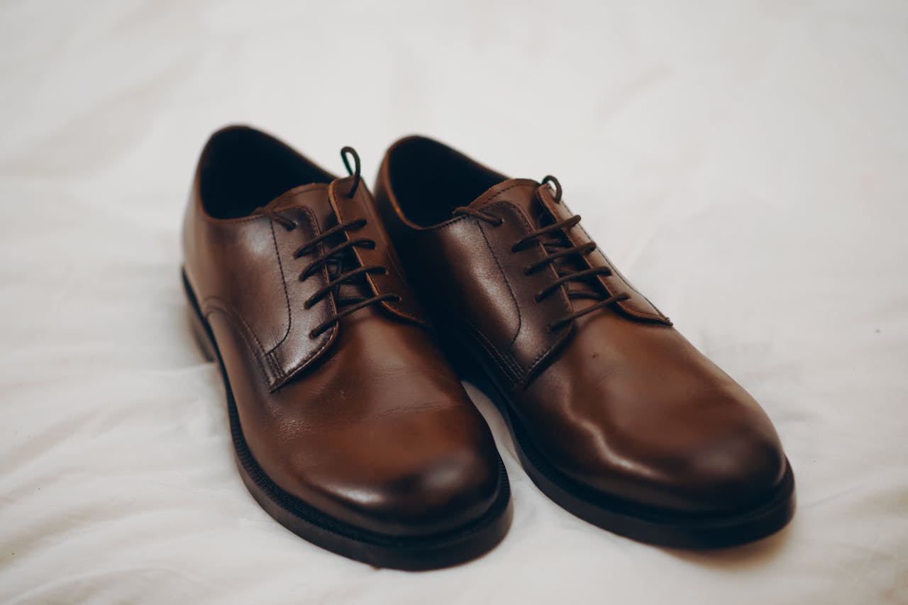 services-04 Pair of classic brown leather dress shoes resting on a white surface.