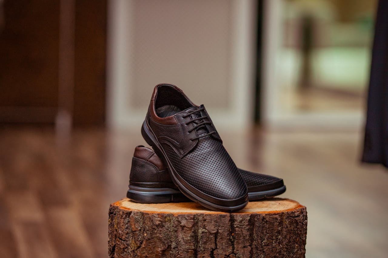 services-03 Stylish perforated leather shoes displayed elegantly on a rustic wooden stump indoors.